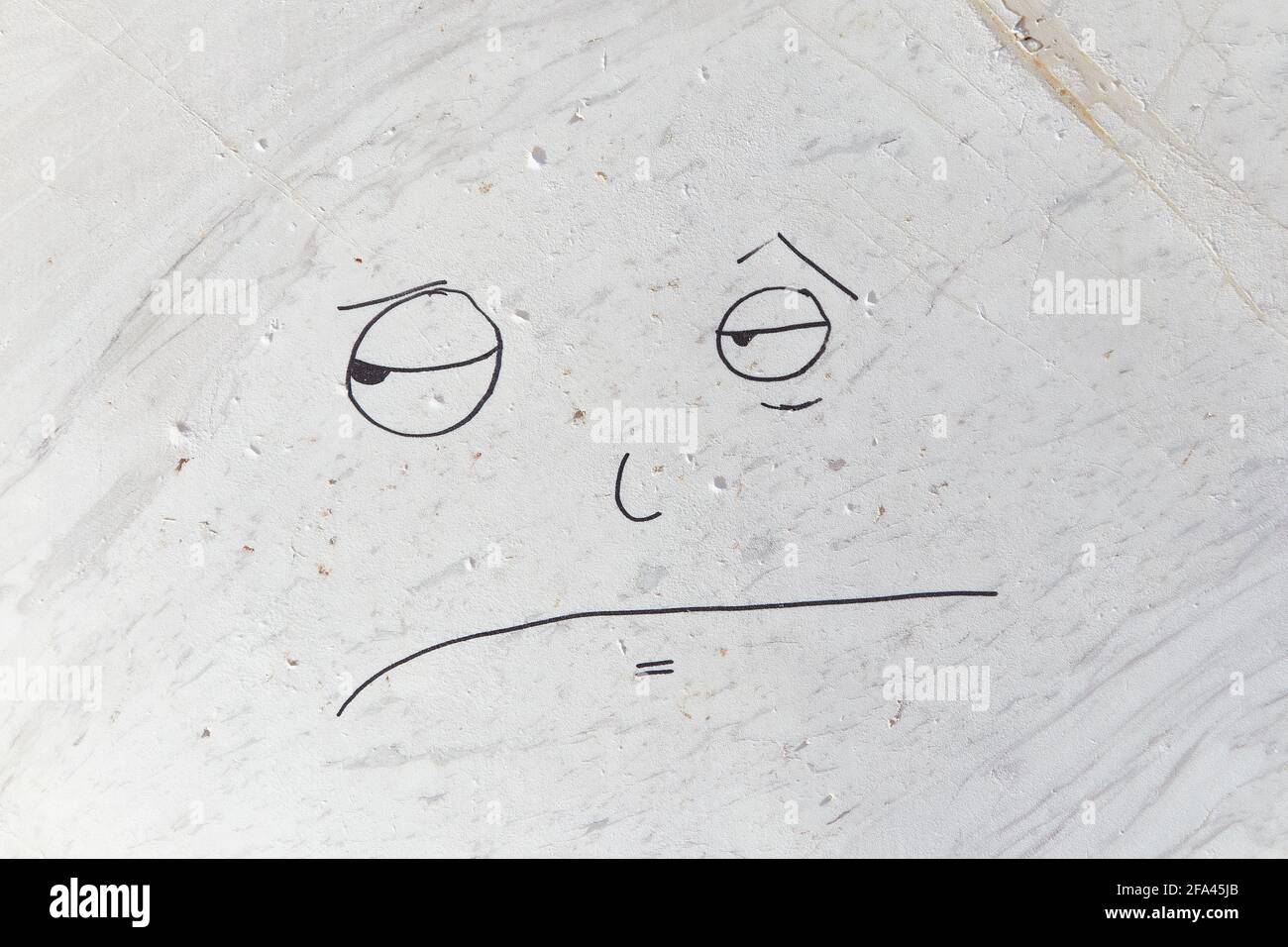 White marble veined surface on which a disgruntled face is drawn Stock Photo