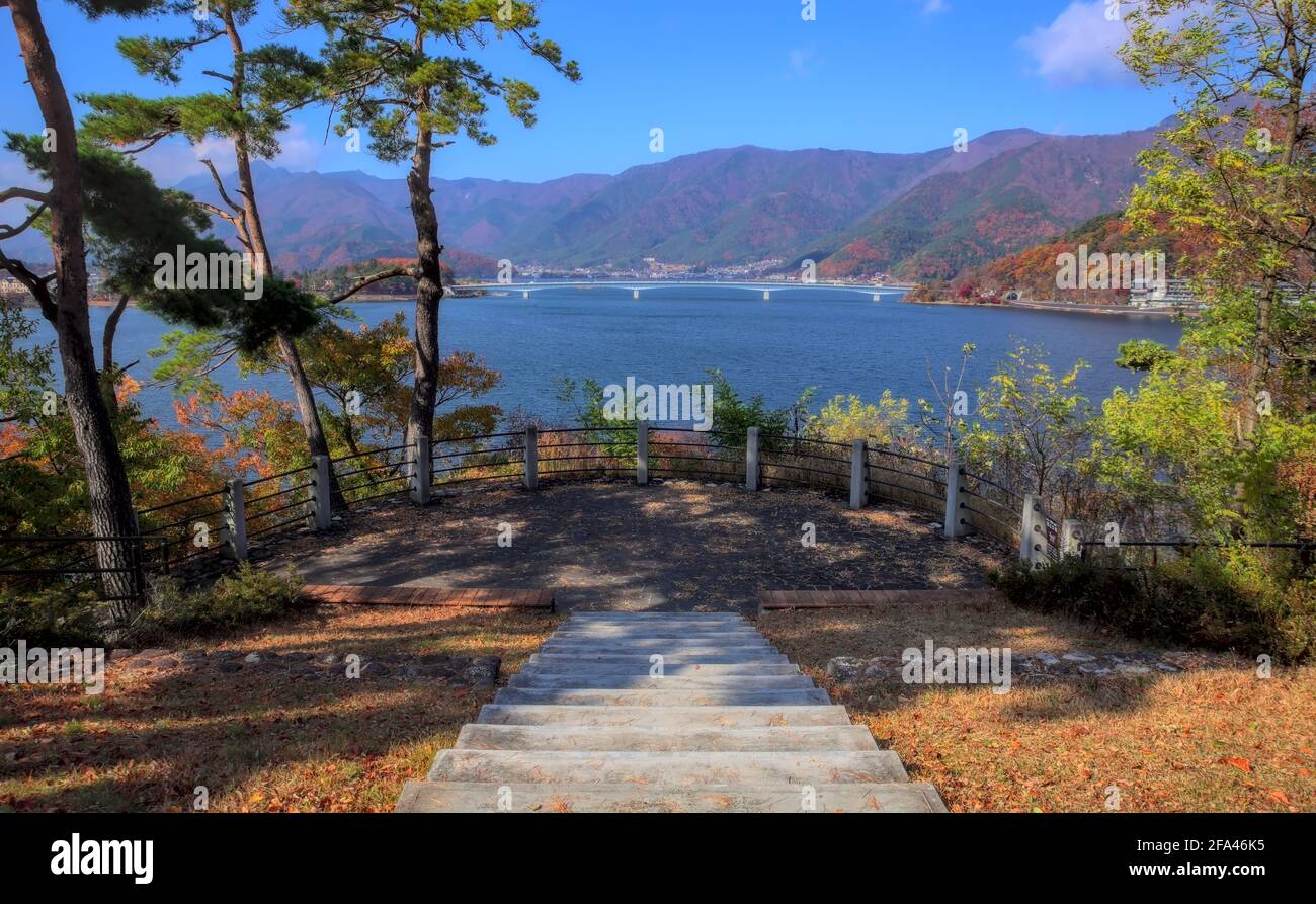 View of paved steps leading down to a small observation platform overlooking Lake Kawaguchi and some surrounding forested mountains on an autumn day Stock Photo