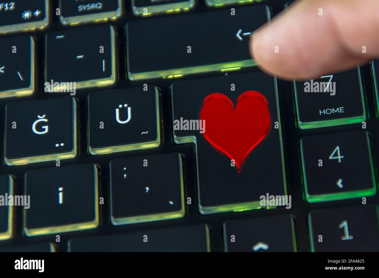 Finger clicking heart icon on black keyboard, online dating site Stock Photo