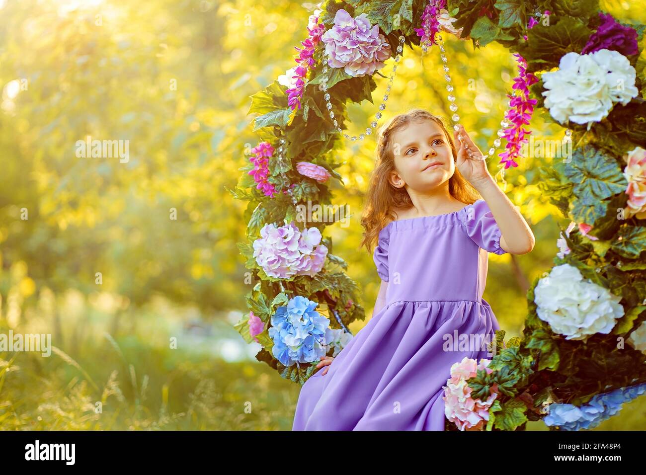 Cute little girl wearing lilac dress posing while sitting in rin Stock Photo Alamy