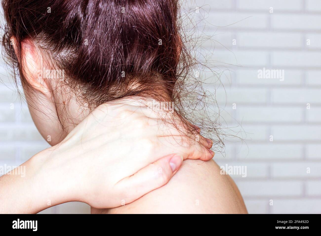 Young caucasian woman with hand on her unhealthy neck and shoulder. Self massage, office syndrome, neck ache and musclar pain concept. Stock Photo