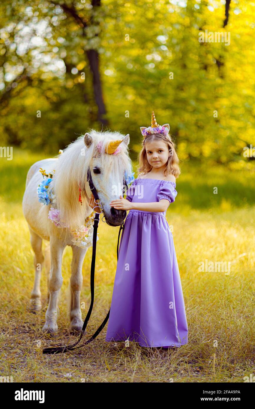 Girl in purple dress with wreath of a unicorn in hair hugging wh Stock  Photo - Alamy