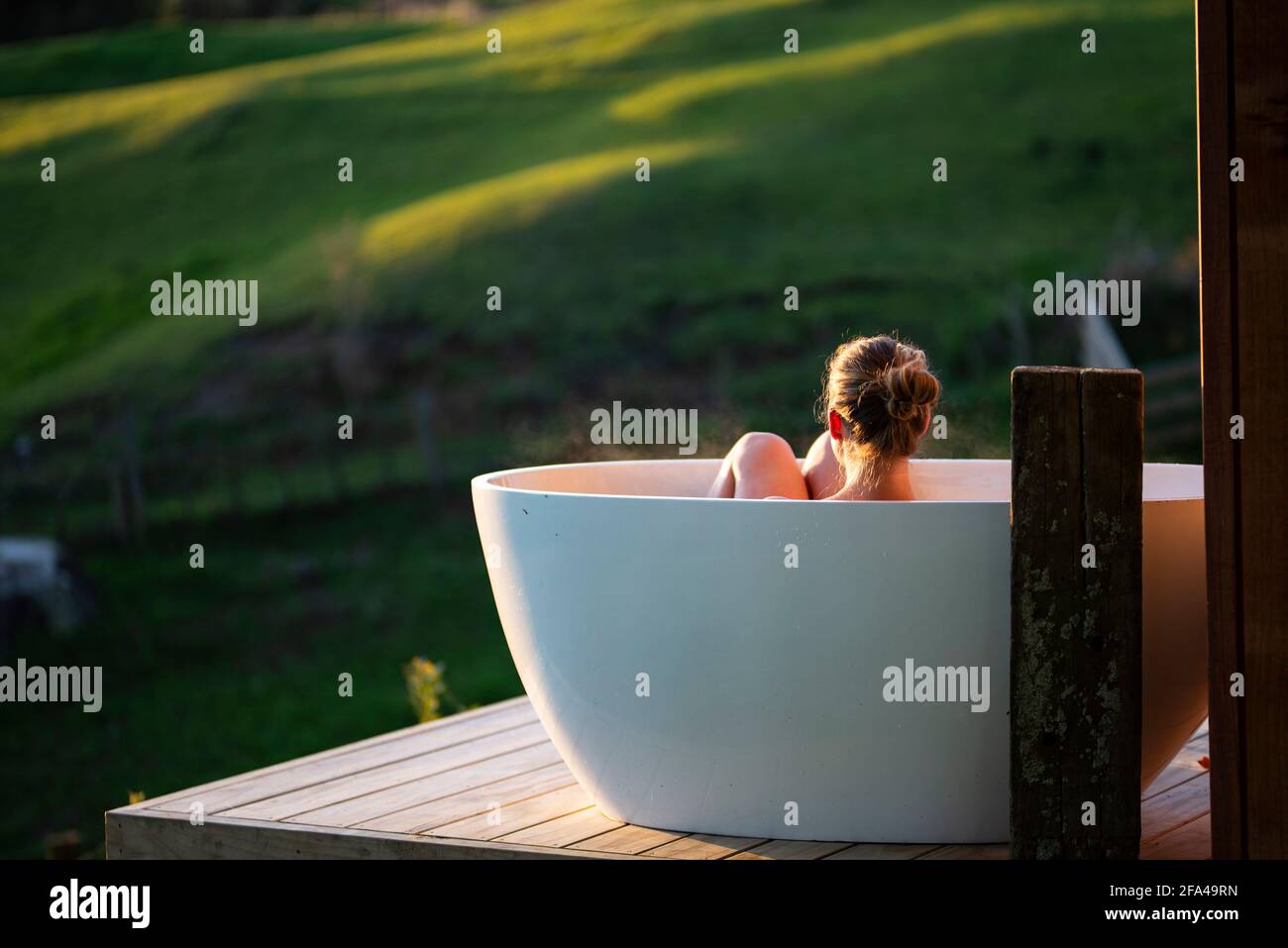 Woman in outdoor bath watching sunset, Rotorua, New Zealand Stock Photo