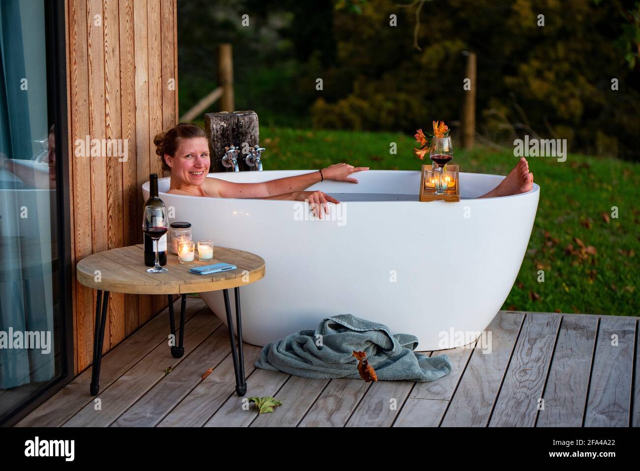 Woman in outdoor bath watching sunset, Rotorua, New Zealand Stock Photo