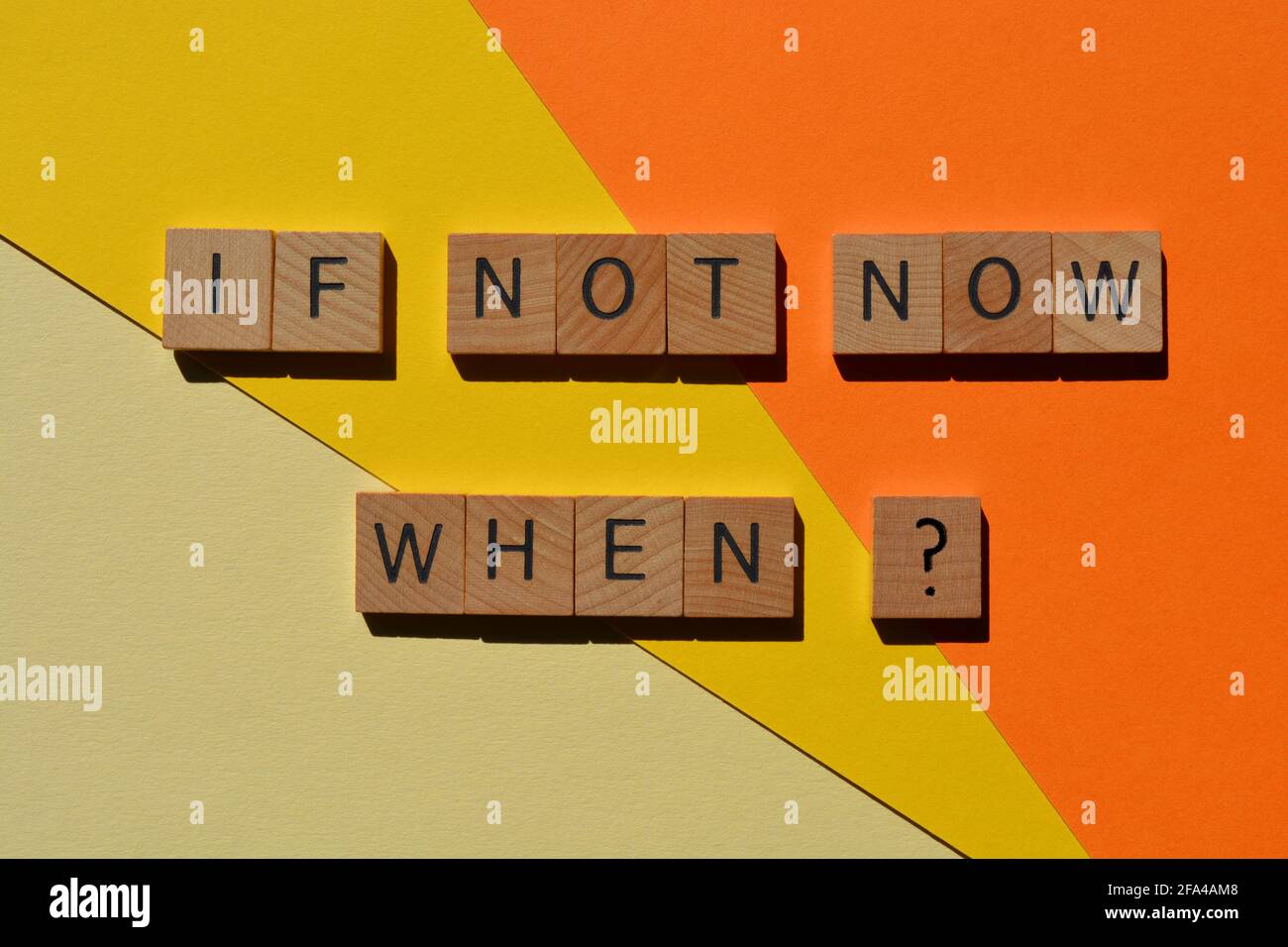 If Not Now When, motivational words in wooden alphabet letters isolated on yellow and orange background Stock Photo