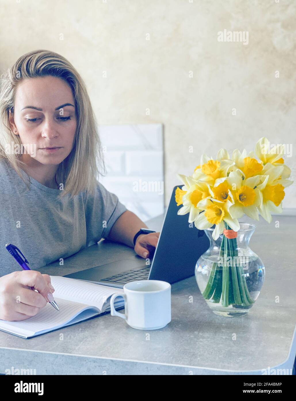 the woman works at the computer and writes in a notebook Stock Photo