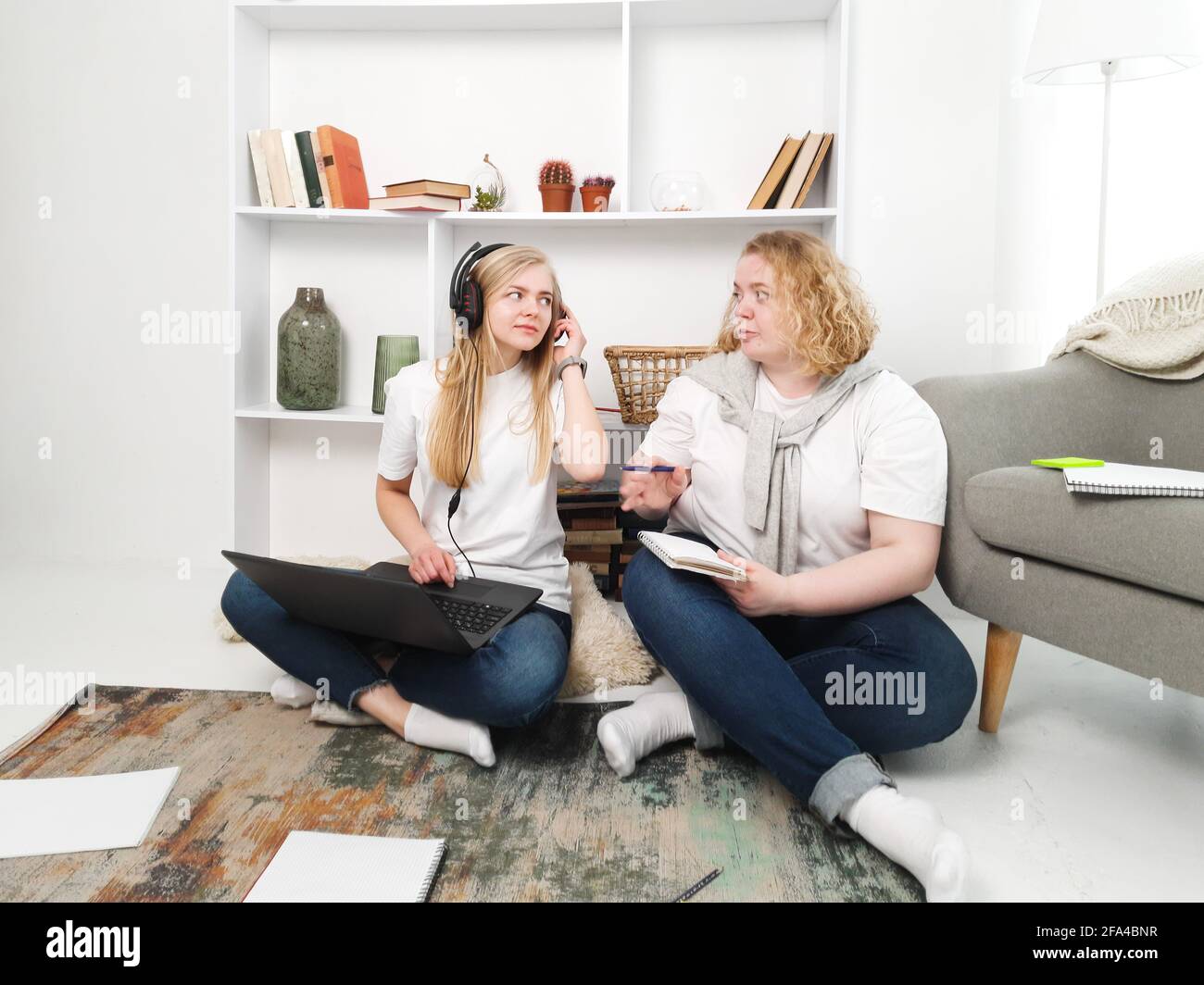 two women studying sitting on the floor with laptop and notebooks Stock ...