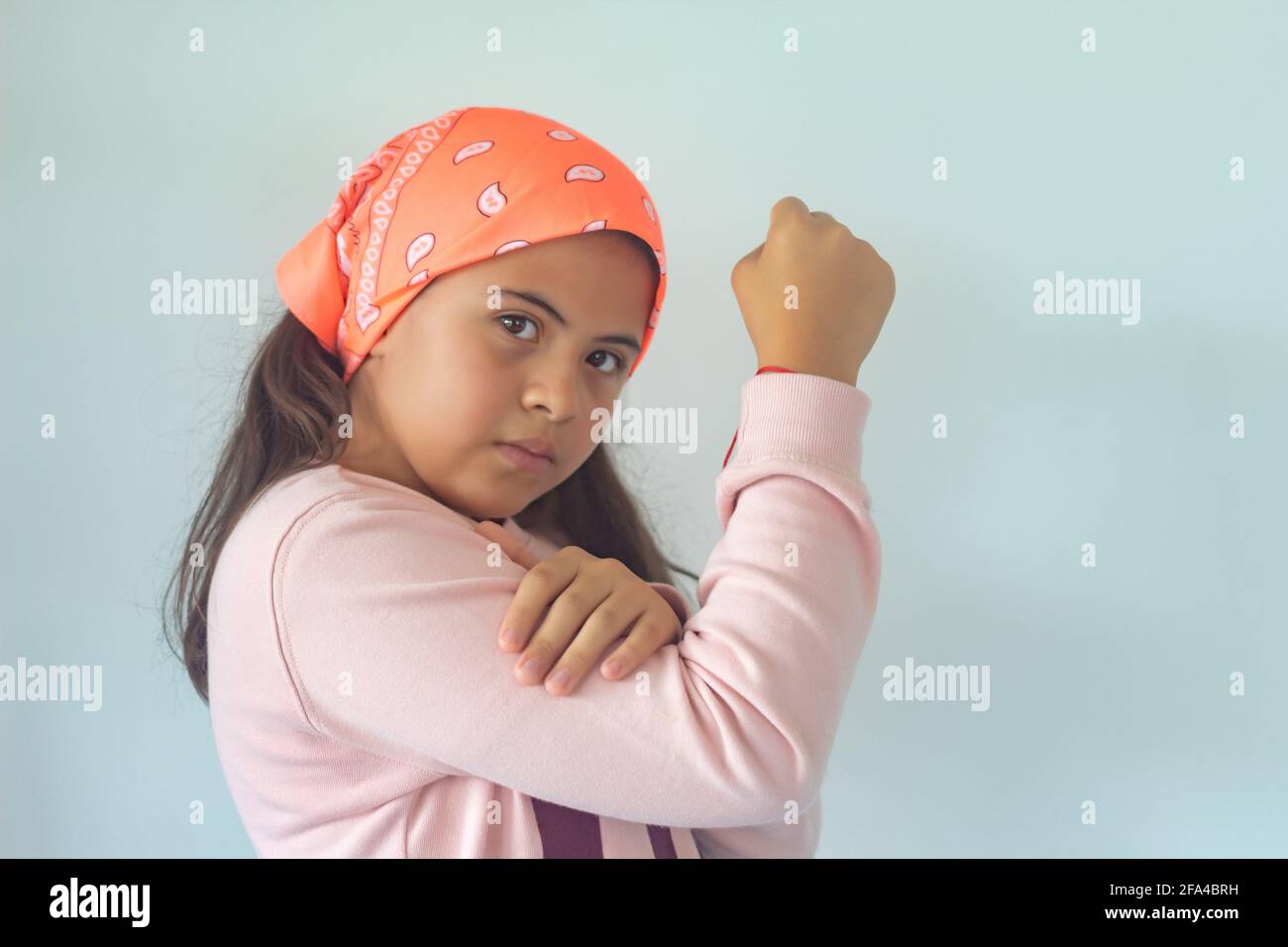 Little Columbiana girl wearing a headscarf smiling and showing the