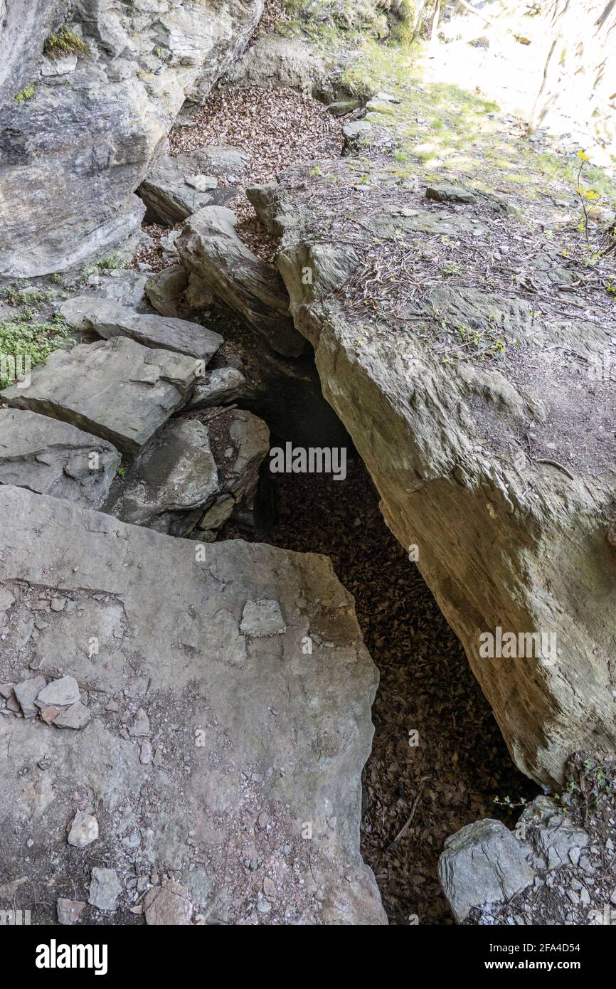 Vertical shot of sharp rocks in a cave in a forest with pebbles and ...
