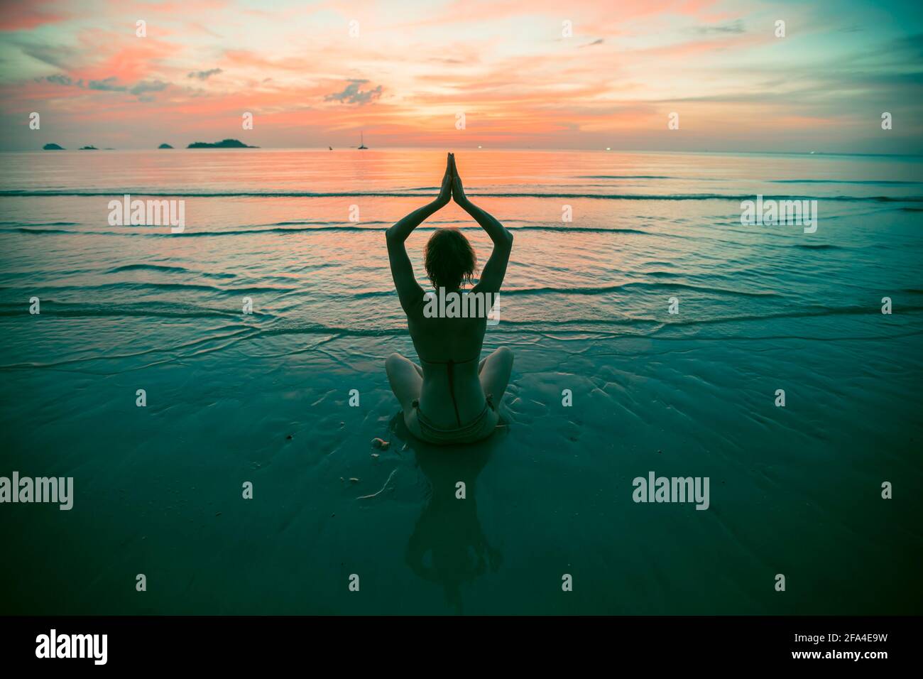 Yoga woman silhouette on the sea beach at amazing sunset. Meditation and healthy lifestyle. Stock Photo