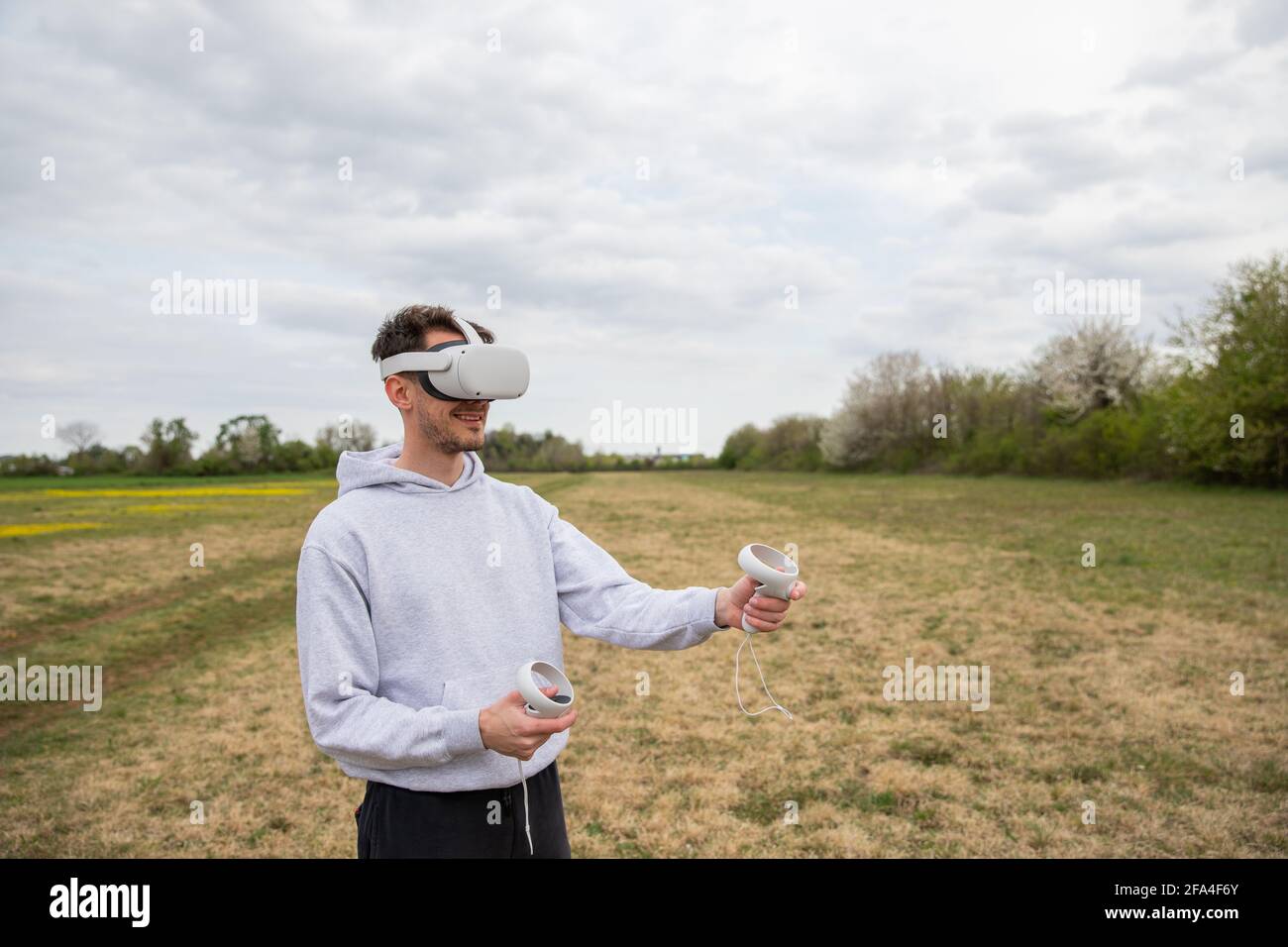 A young boy plays with his VR headset and controllers in a lawn in open ...