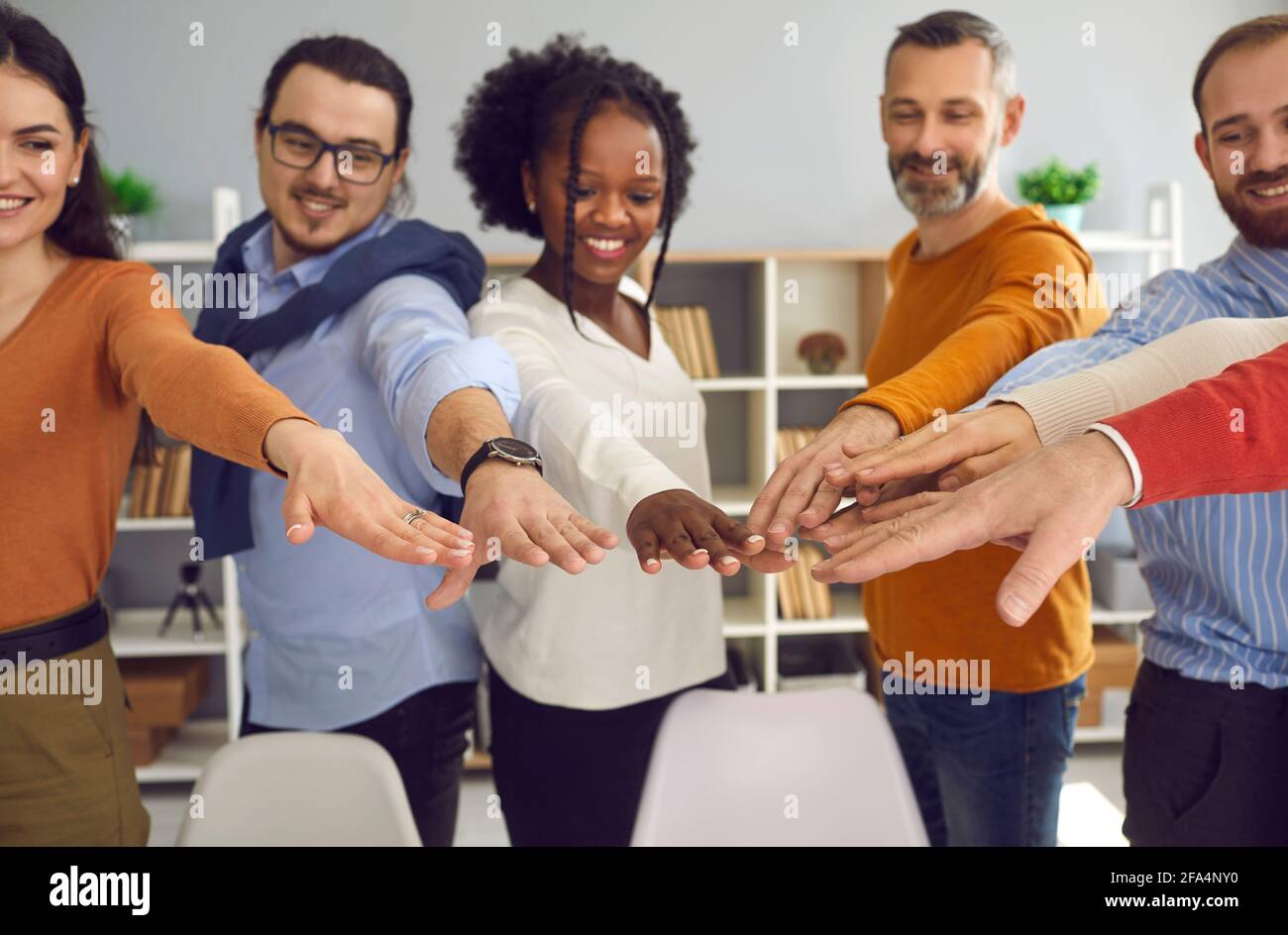 Group of diverse multiethnic people joining hands together front view shot Stock Photo