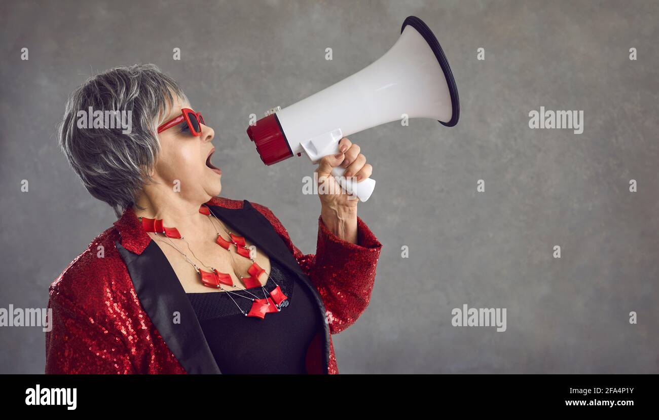 Funky eccentric senior woman yelling in a megaphone announcing a crazy blowout sale Stock Photo