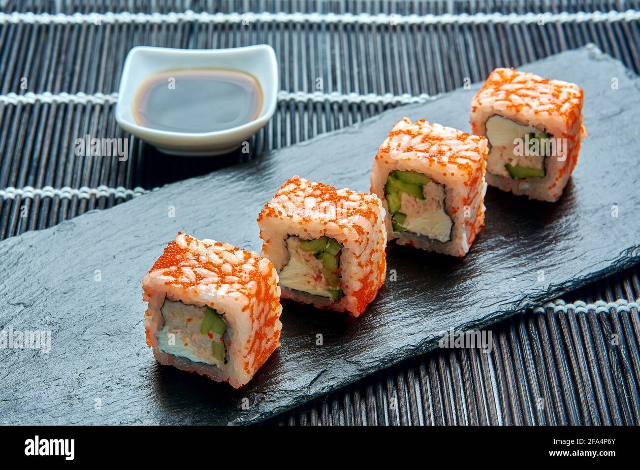 Philadelphia roll classic with red caviar on a dark stone on the board. Japanese sushi. Stock Photo