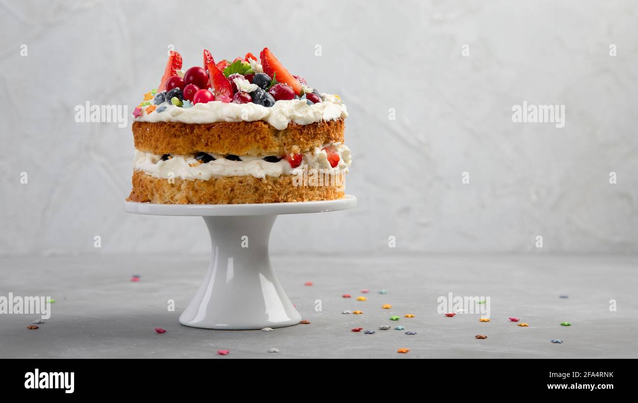 Delicious homemade cake with fresh berries and mascarpone cream on gray background. Stock Photo