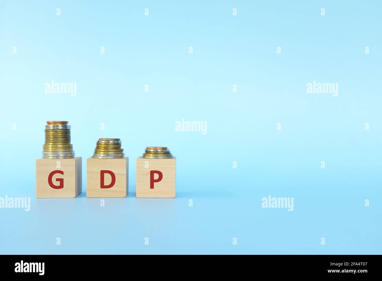 GDP or gross domestic product letters in wooden blocks with decreasing stack of coins. Economic crisis, decline and recession concept. Stock Photo
