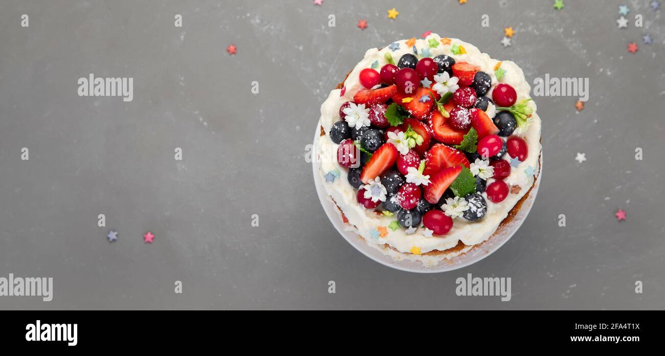 Delicious homemade cake with fresh berries and mascarpone cream on gray background. Top view, copy space. Panorama, banner Stock Photo