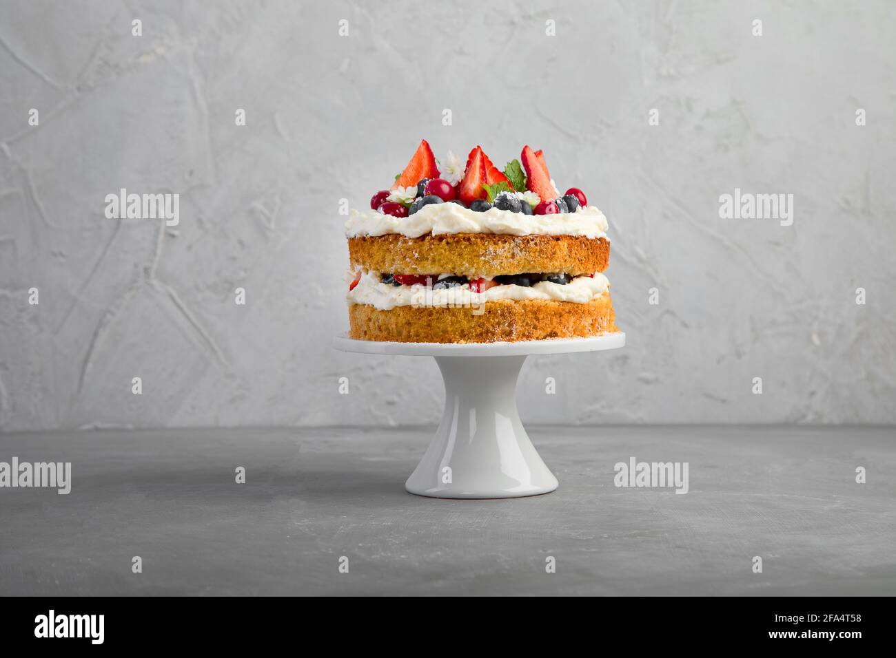 Delicious homemade cake with fresh berries and mascarpone cream on gray background. Stock Photo