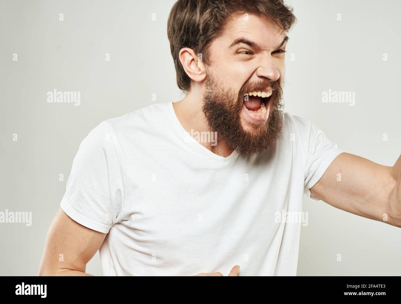 emotional man gesturing with his hands on a light background aggression ...
