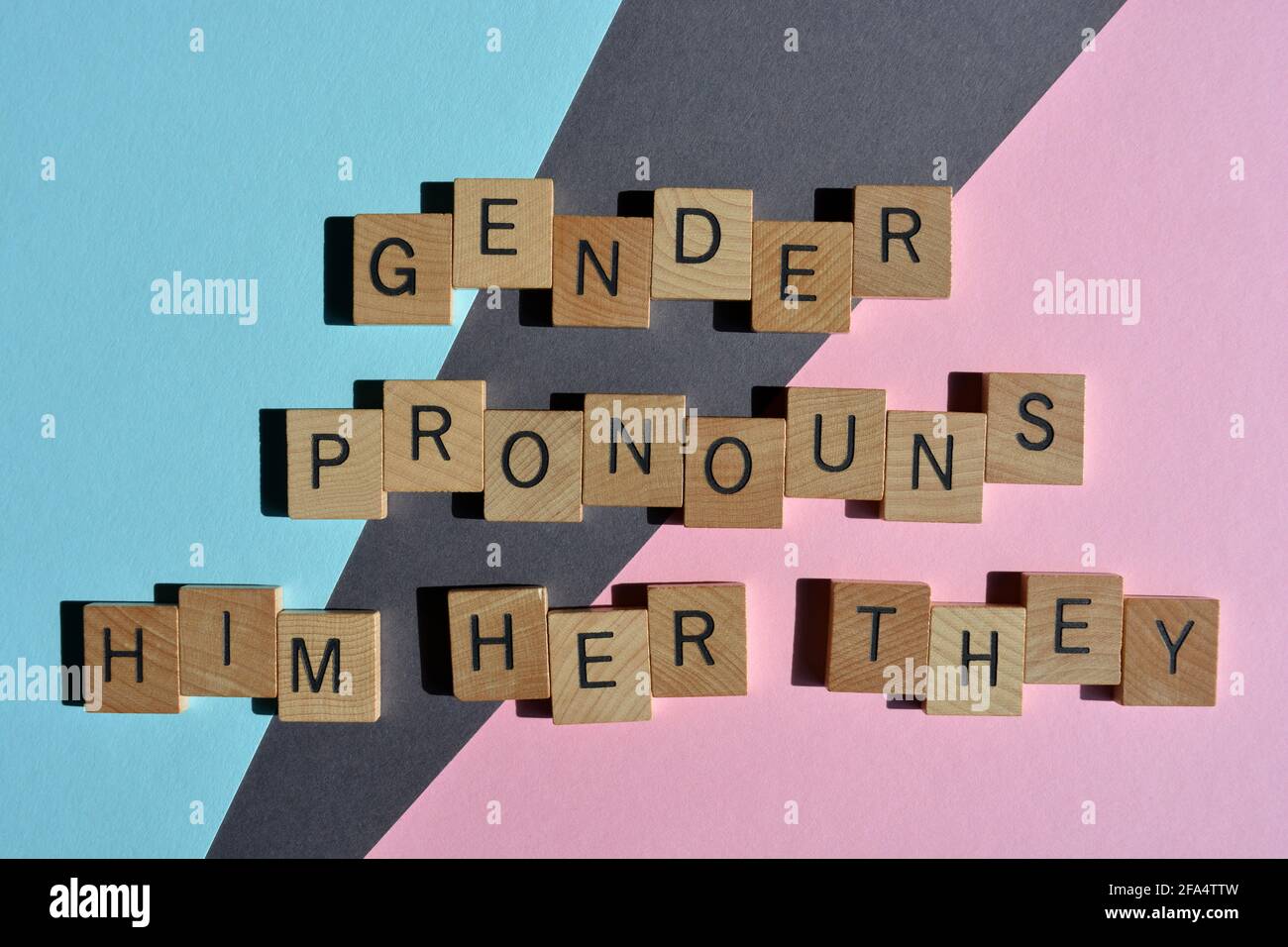 Gender Pronouns, Him, Her, They, words in wooden alphabet letters isolated on blue, grey and pink background Stock Photo