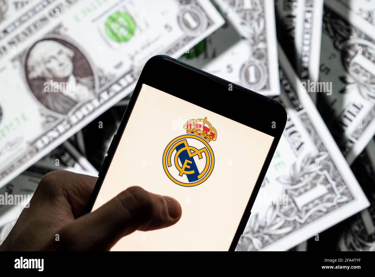 China. 21st Apr, 2021. In this photo illustration Spanish professional football club team Real Madrid Club de FÃºtbol commonly known as Real Madrid logo seen on an Android mobile device screen with the currency of the United States dollar icon, $ icon symbol in the background. Credit: Budrul Chukrut/SOPA Images/ZUMA Wire/Alamy Live News Stock Photo
