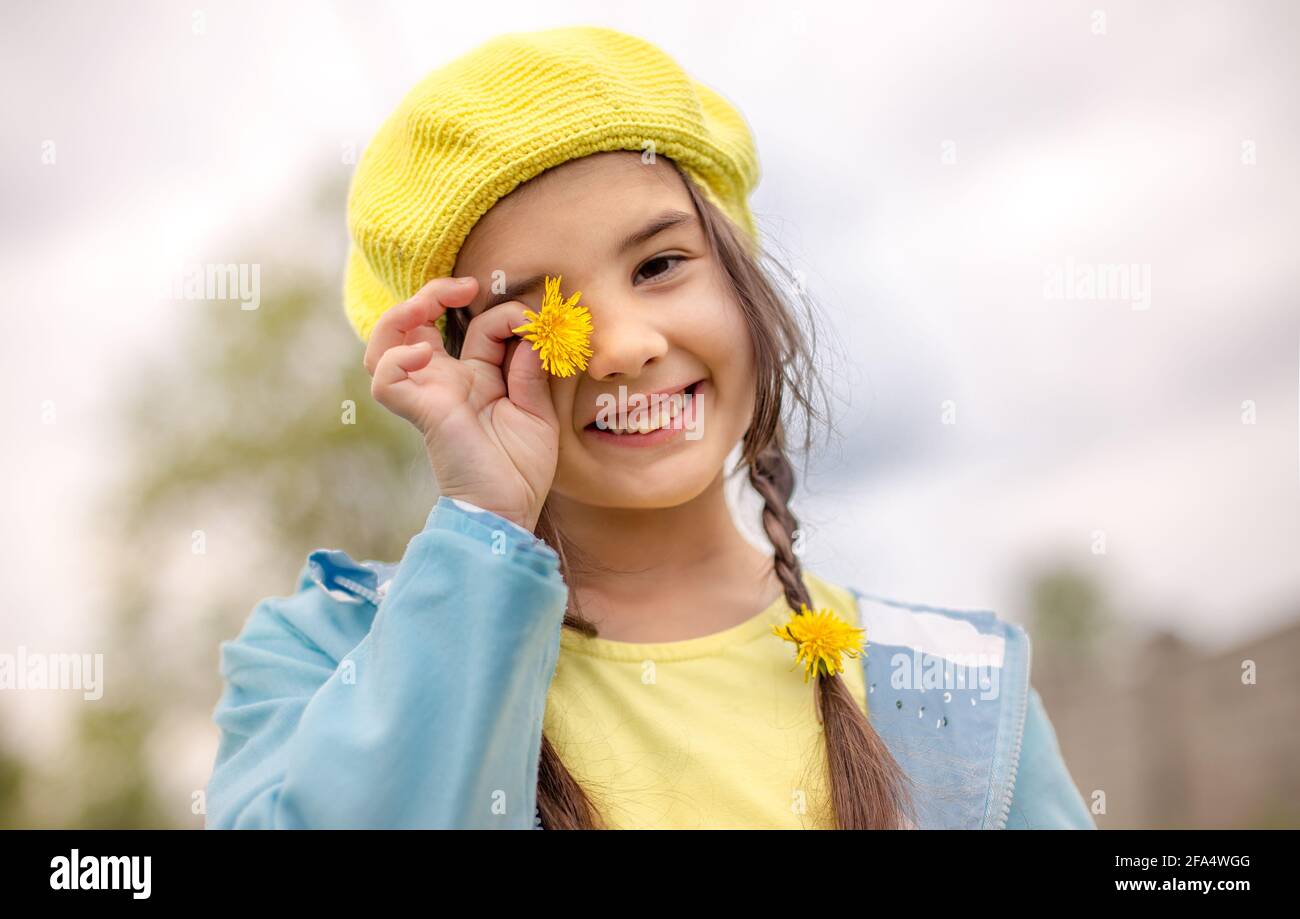 Portrait of a funny charming little girl with two pigtails, in a yellow knitted beret Stock Photo