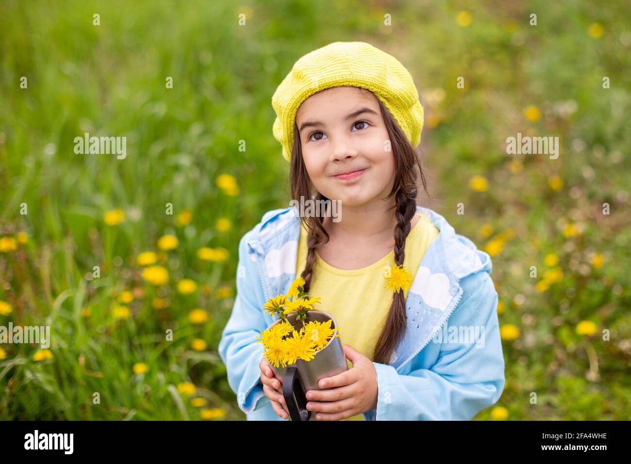 Portrait of a beautiful little girl with two pigtails holds a bouquet ...