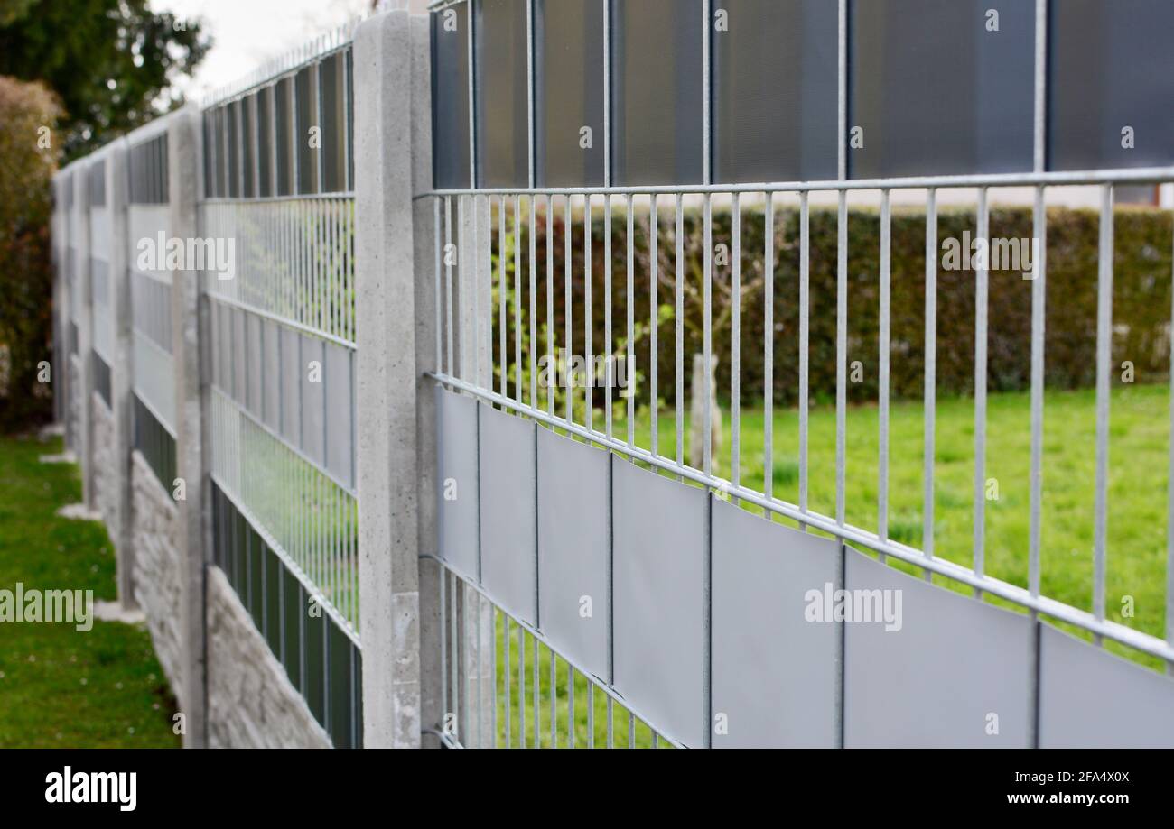 Garden fence made with decorative galvanized wire fence panels inserted in to the concrete columns. Stock Photo