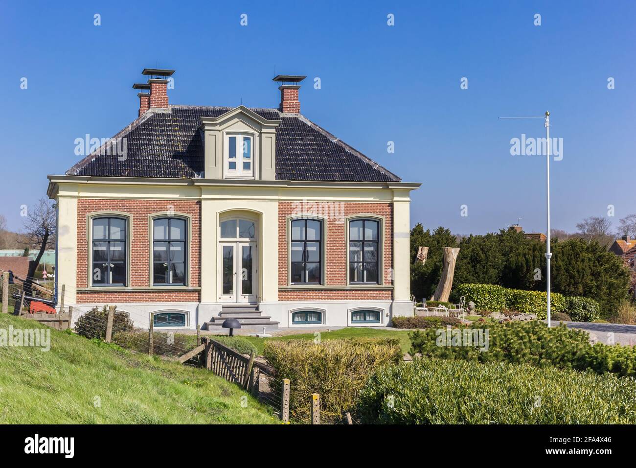 Historic house behind the dike in Zoutkamp, Netherlands Stock Photo