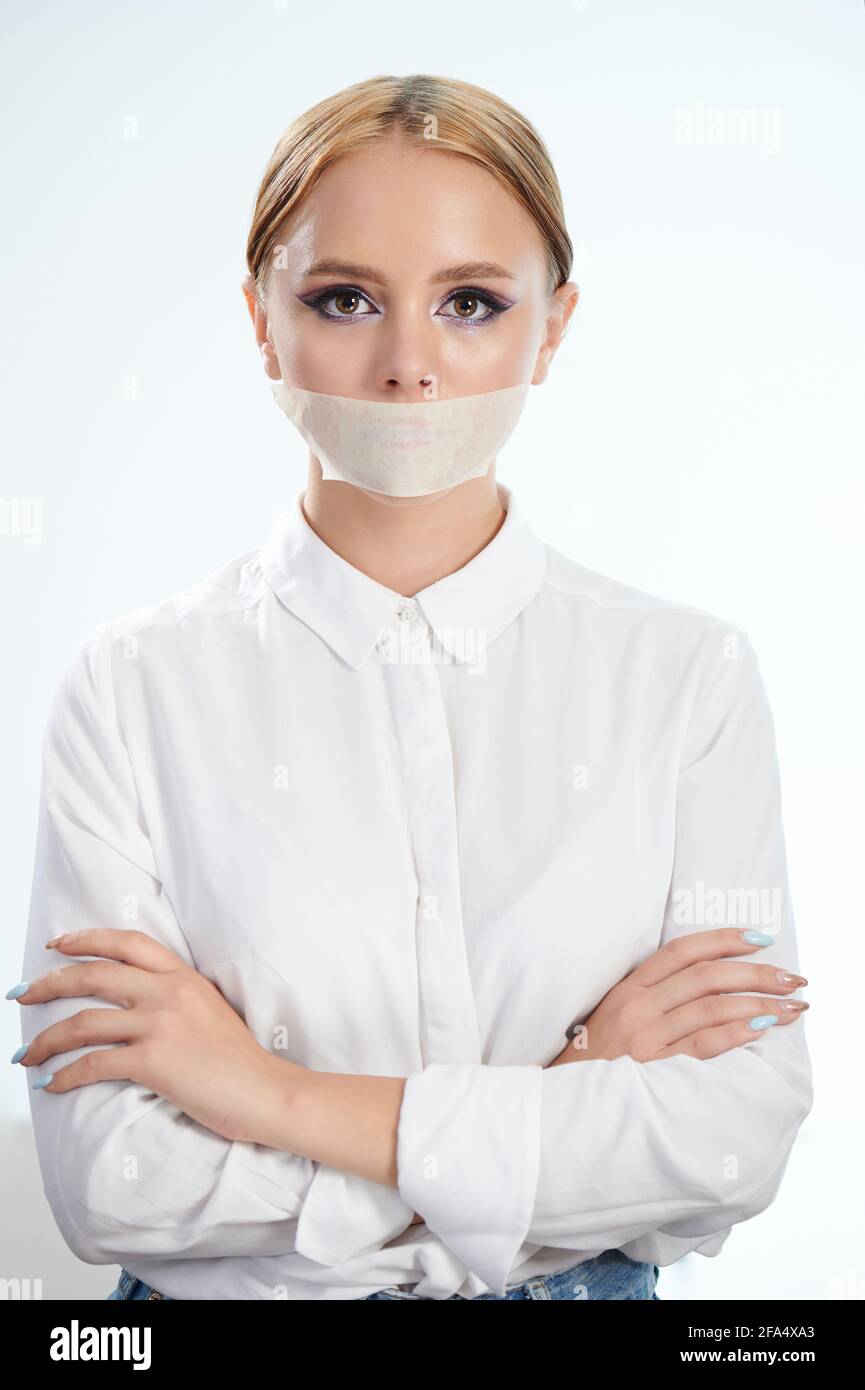 Woman right censorship. Girl with closed mouth and crossed hands on studio background Stock Photo