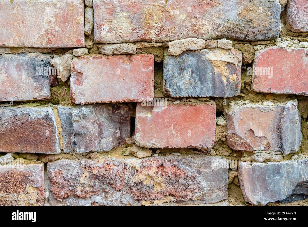 The old brickwork is made of fragments of red building bricks and holes in the seams. Background image Stock Photo