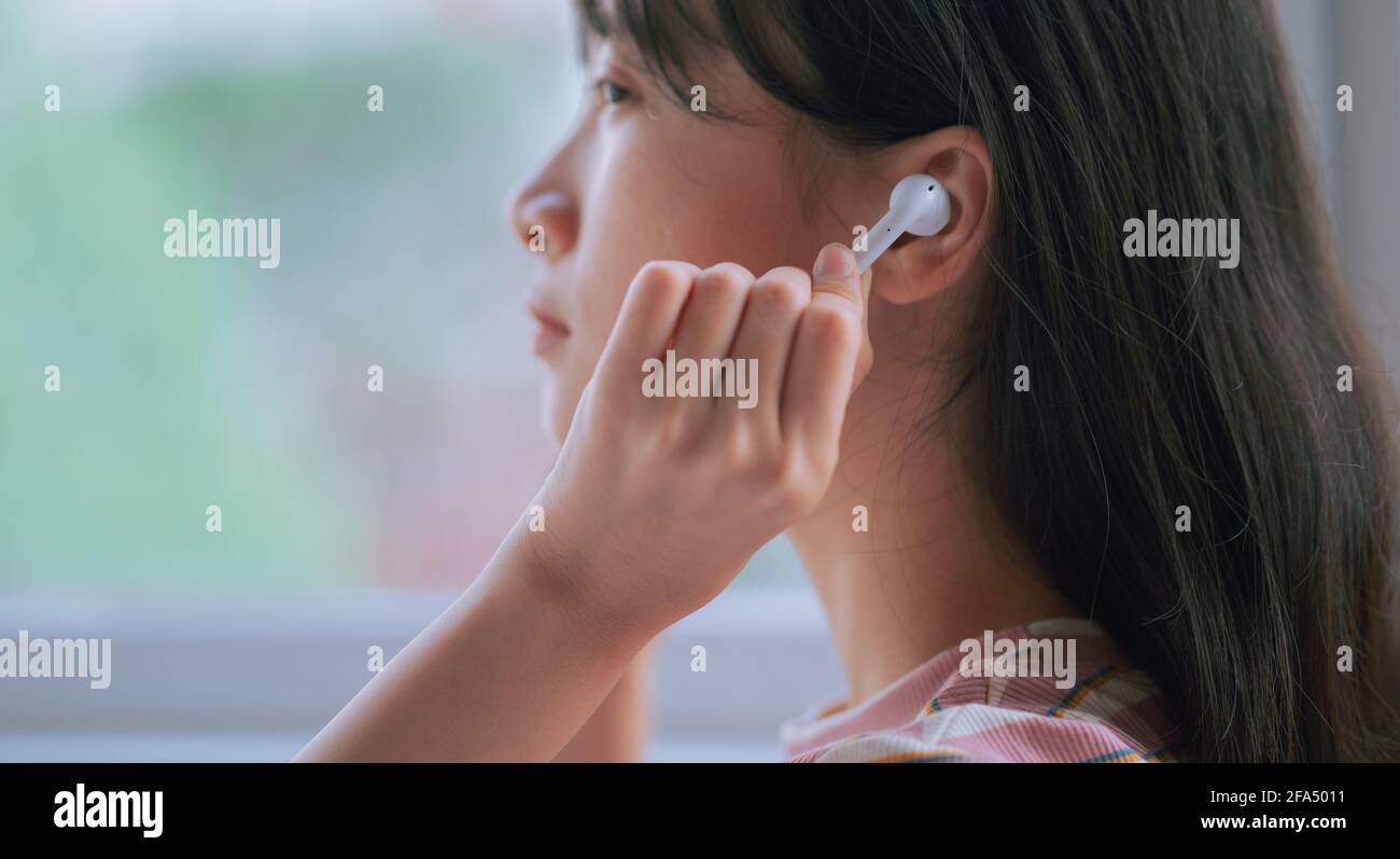 Young Asian woman using wireless earphones to listen music Stock Photo ...