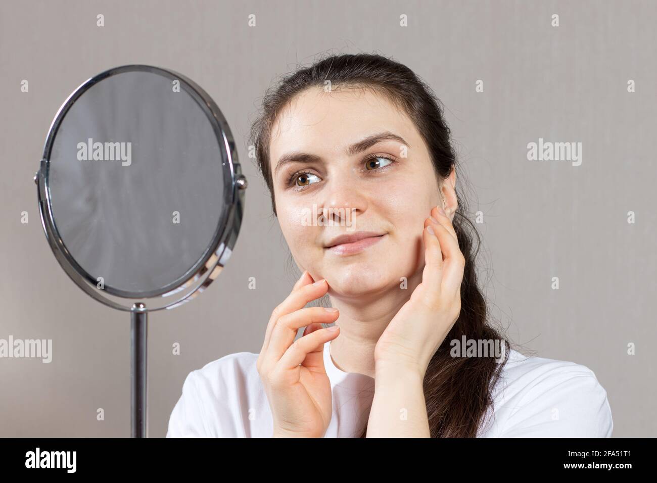 A beautiful young brunette woman 20 30 years old looks in the mirror