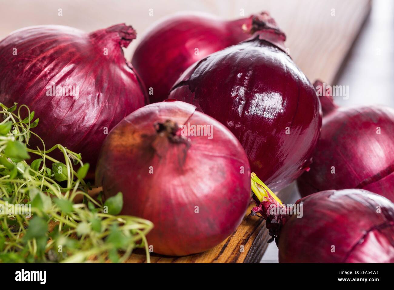 Red onions with thyme on wooden board. Stock Photo