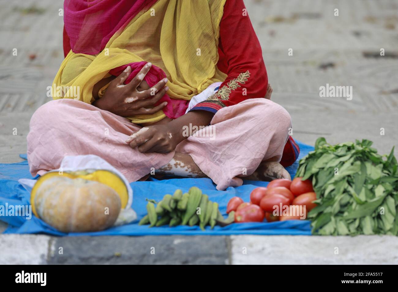 Please hide child's face prior to the publication - Asma Begum holding her three-month daughter, sells vegetable on the footpath in Dhaka University area as her husband lost his manhole cleaning job due to the countrywide Coivd-19 restrictions, in Dhaka, Bangladesh, April 22, 2021. Photo by Suvra Anti Das/ABACAPRESS.COM Stock Photo