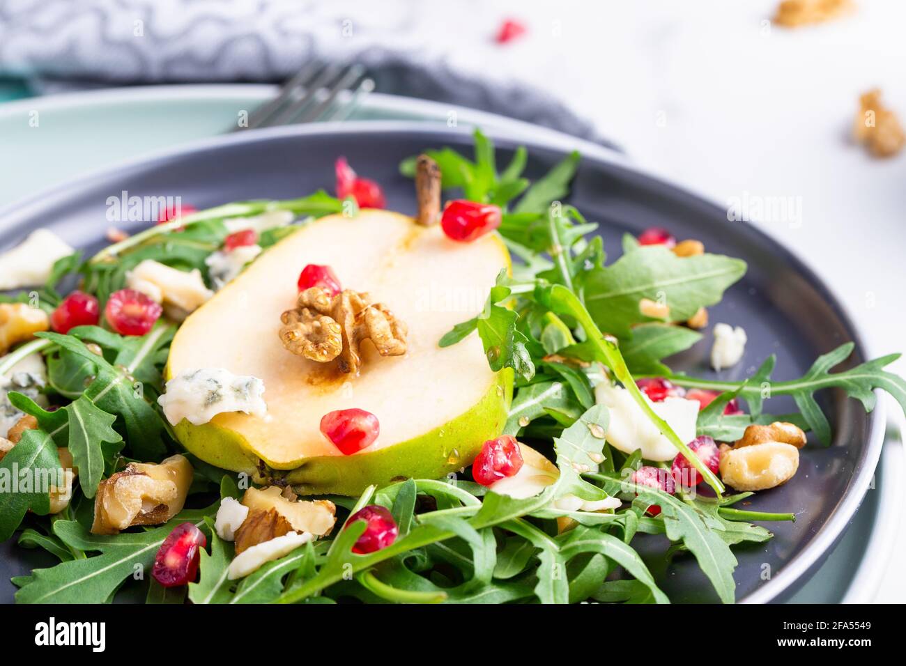 Fresh and healthy salad with arugula, gorgonzola cheese, pomegranate and pears. Stock Photo