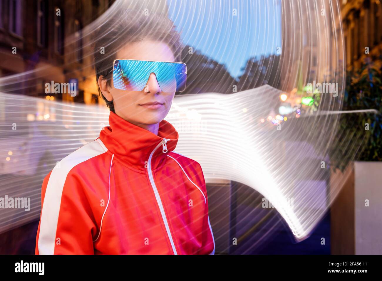 portrait of young woman outdoor on long exposure. young woman in sunglasses wearing for night club techno party posing on background with abstract pat Stock Photo