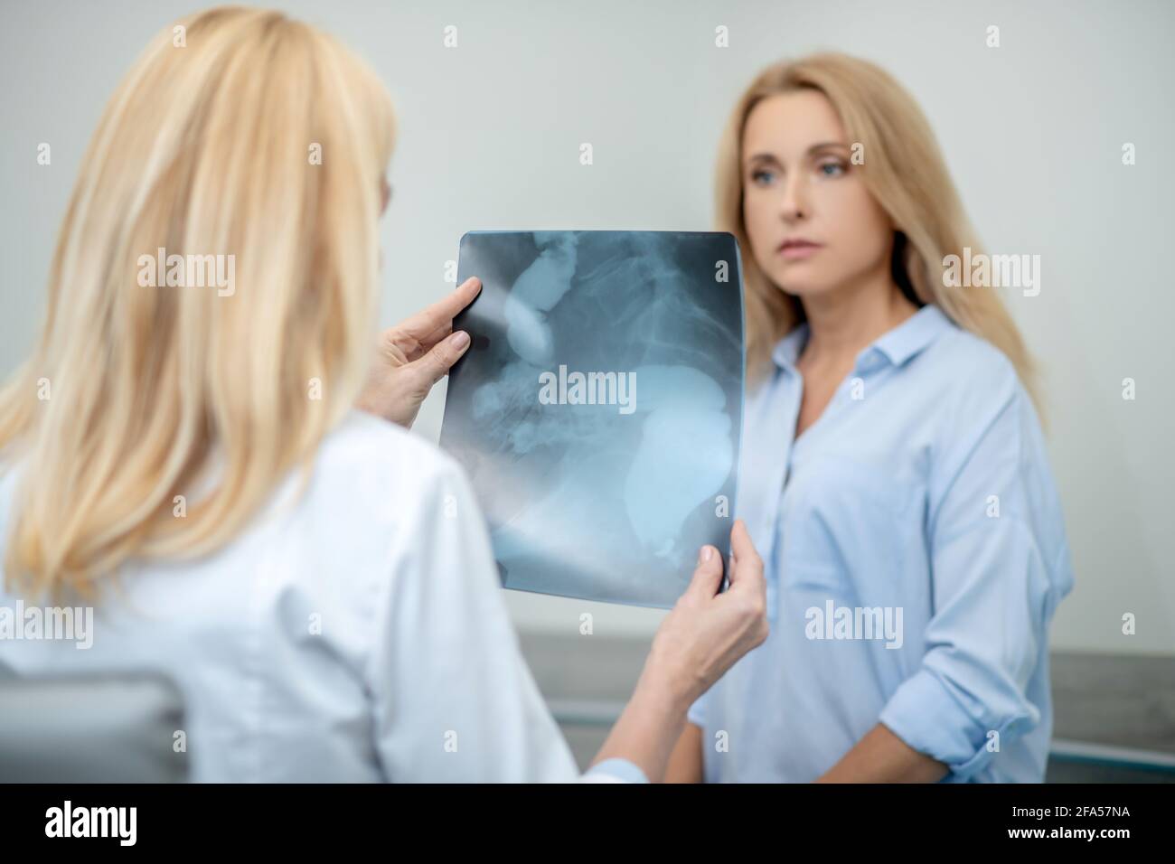 Doctor with back to camera showing x-ray to patient Stock Photo