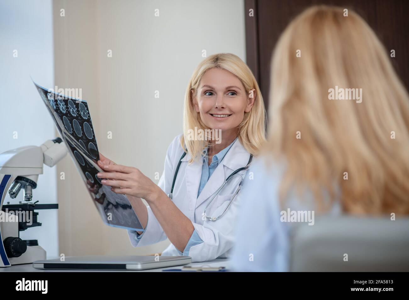 Smiling doctor with MRT scan and patient back Stock Photo
