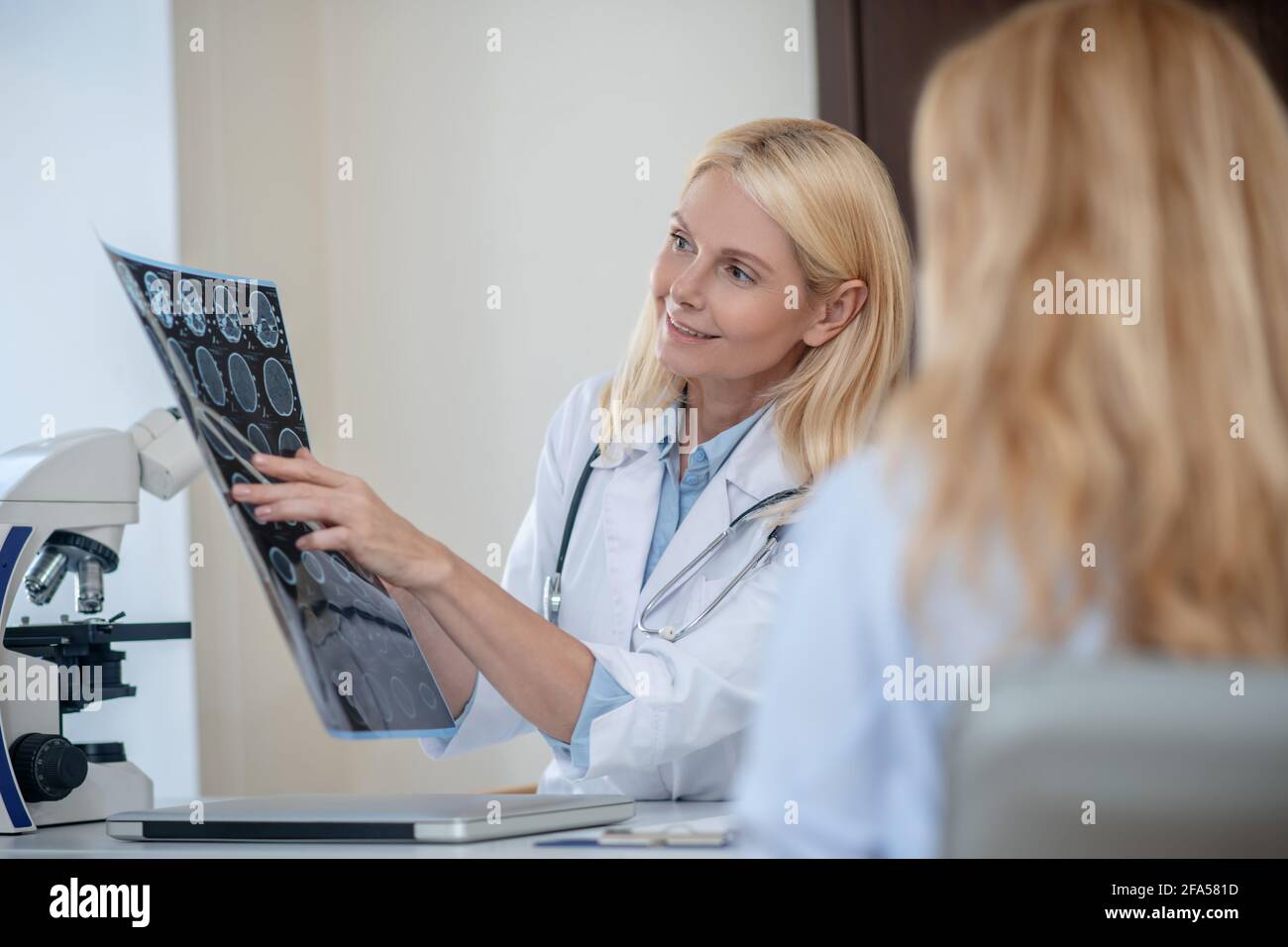 Doctor deciphering MRT scan showing it to patient Stock Photo