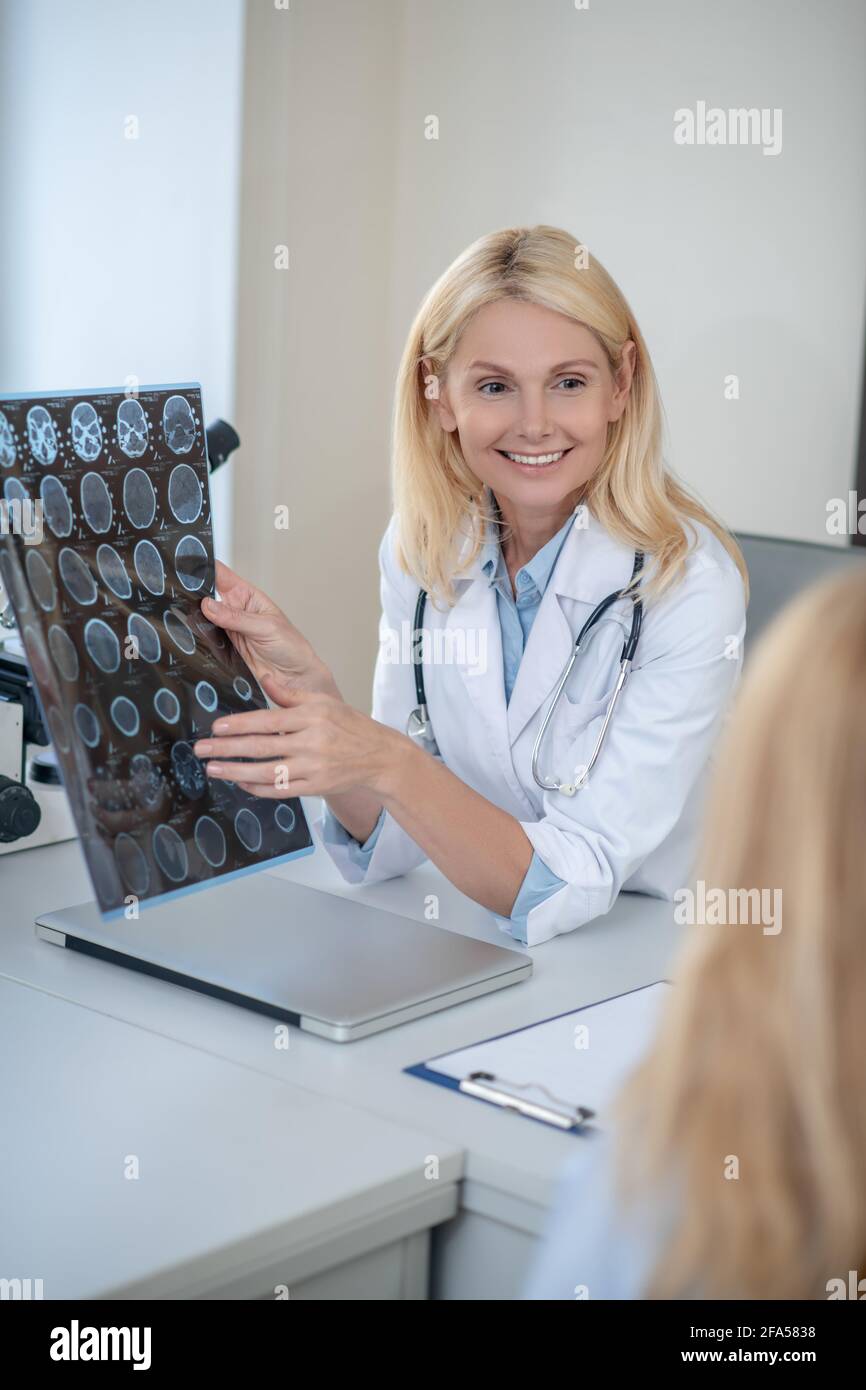 Joyful doctor showing MRT scan to patient Stock Photo