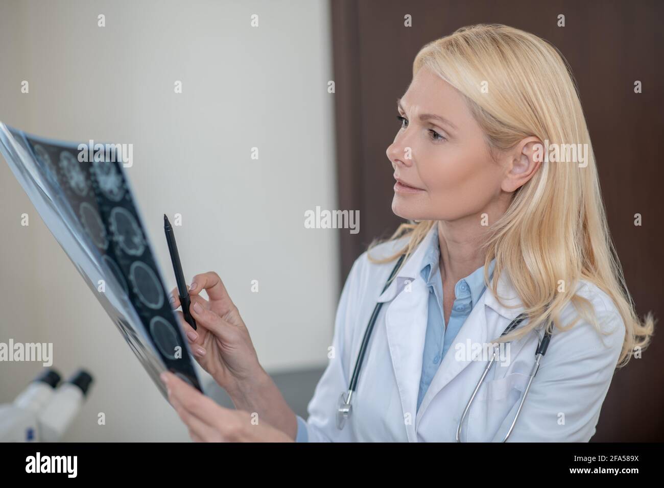 Thinking attentive female doctor with MRT scan in hand Stock Photo