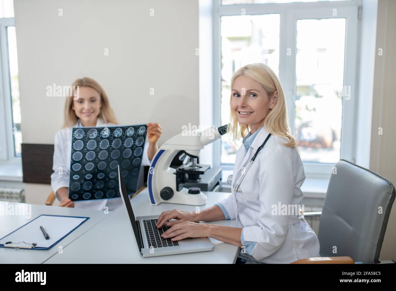 Woman doctor at laptop and colleague with MRT scan Stock Photo
