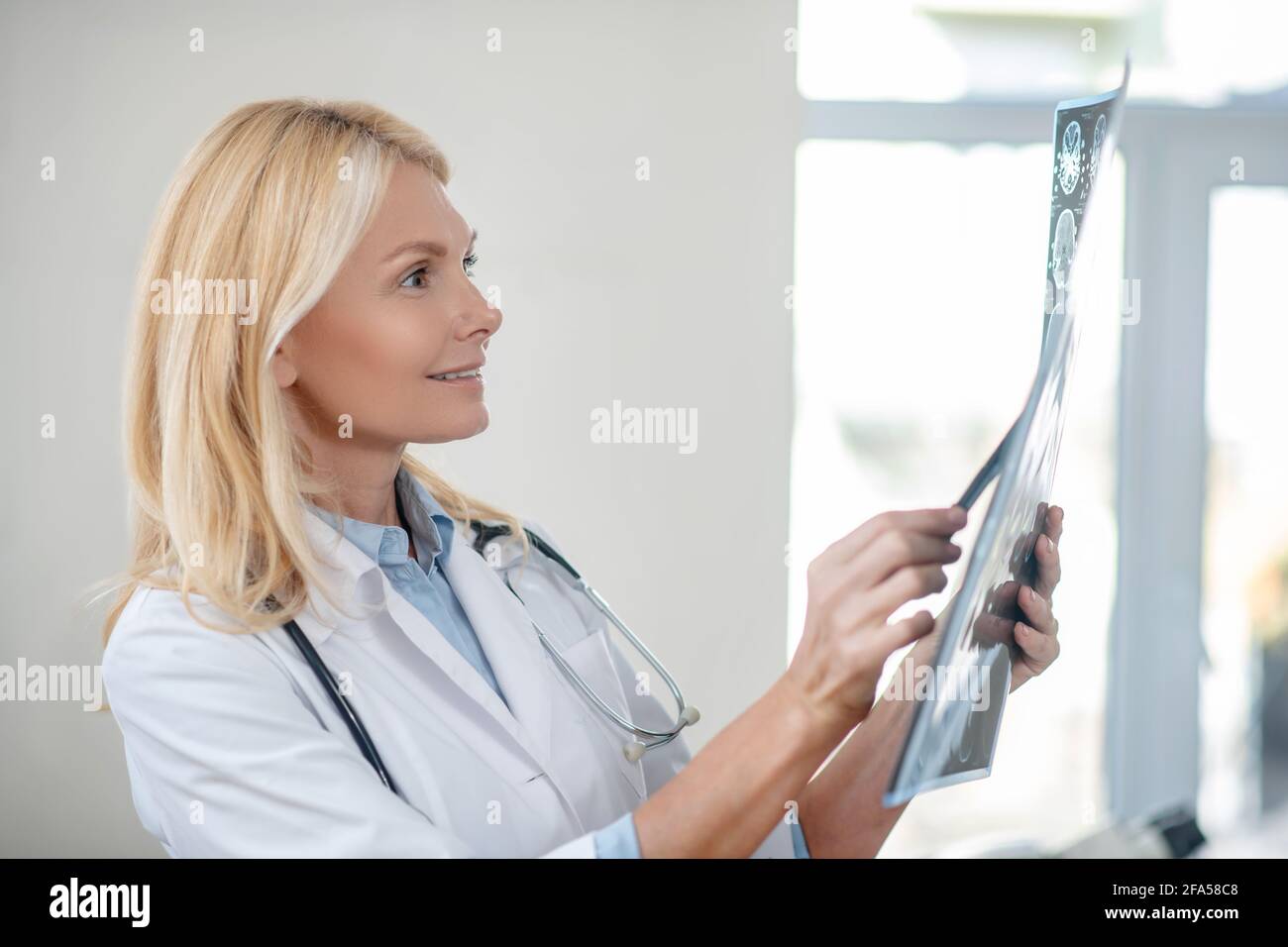 Profile of joyful female doctor considering MRT scan Stock Photo