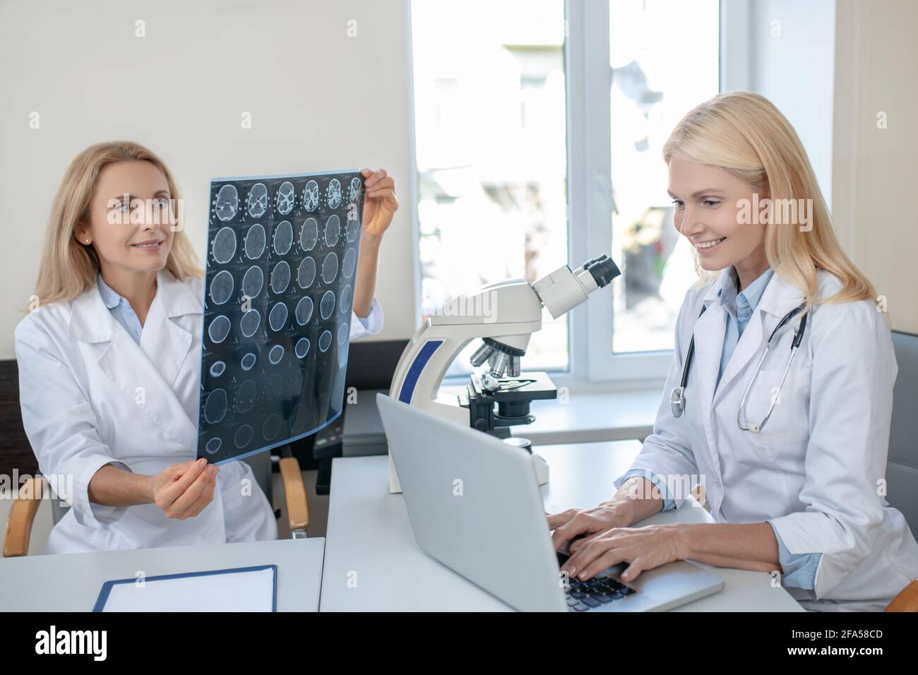 Two women in medical gowns are busy in office Stock Photo