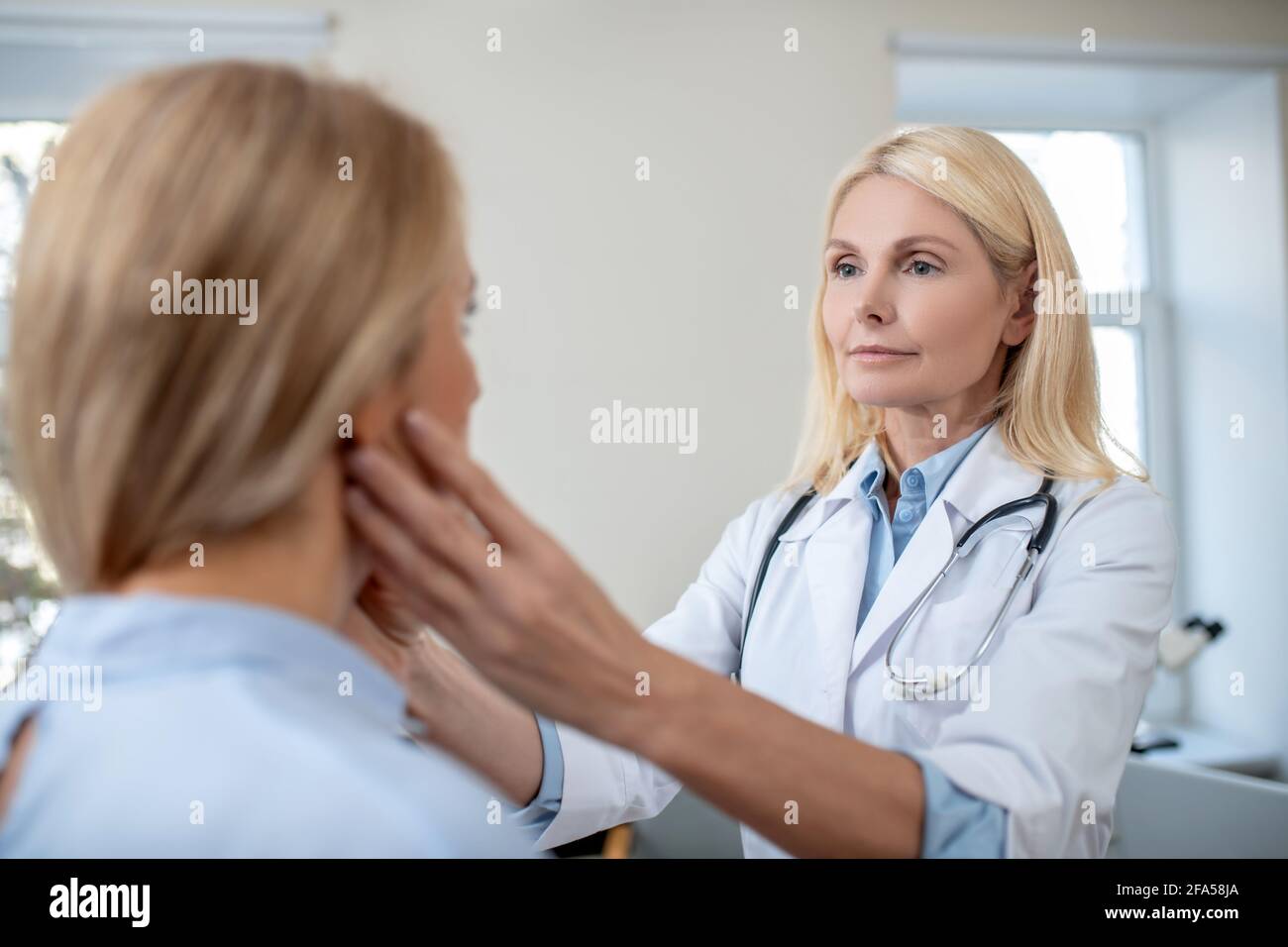 Doctor touching patients neck with his hands Stock Photo