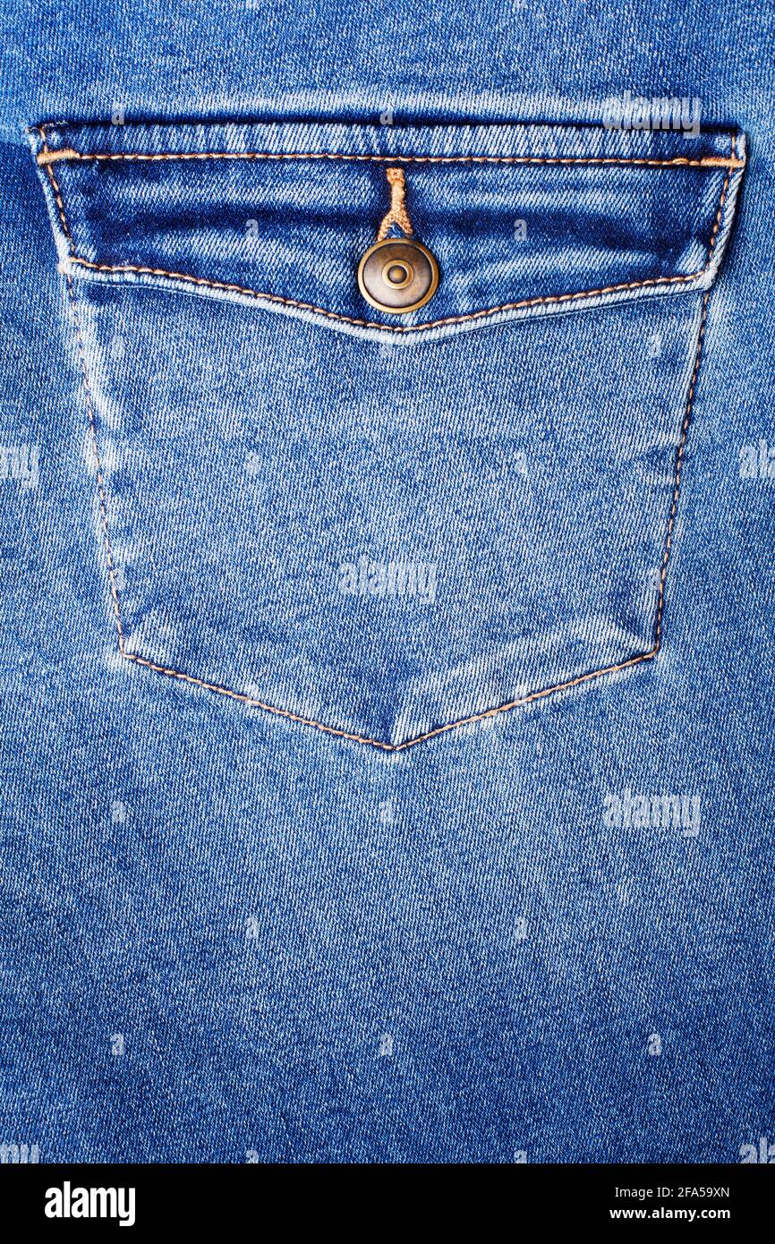 Blue jeans pocket with flap and brass metal button close up, jeans pocket background, blue denim backdrop, jeans pocket pattern, indigo jeans pants Stock Photo