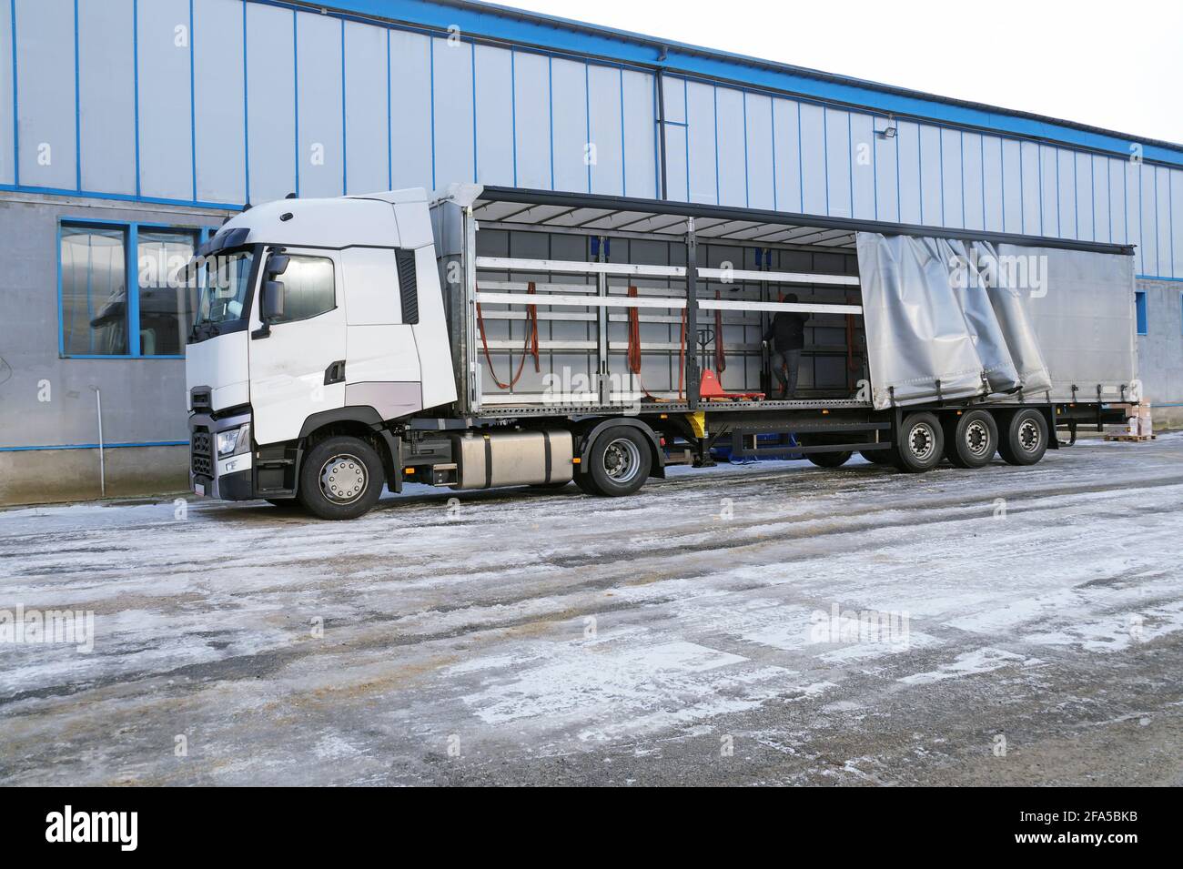 Transport and unloading. Truck and semi-trailer with an exposed tarpaulin  during unloading Stock Photo - Alamy