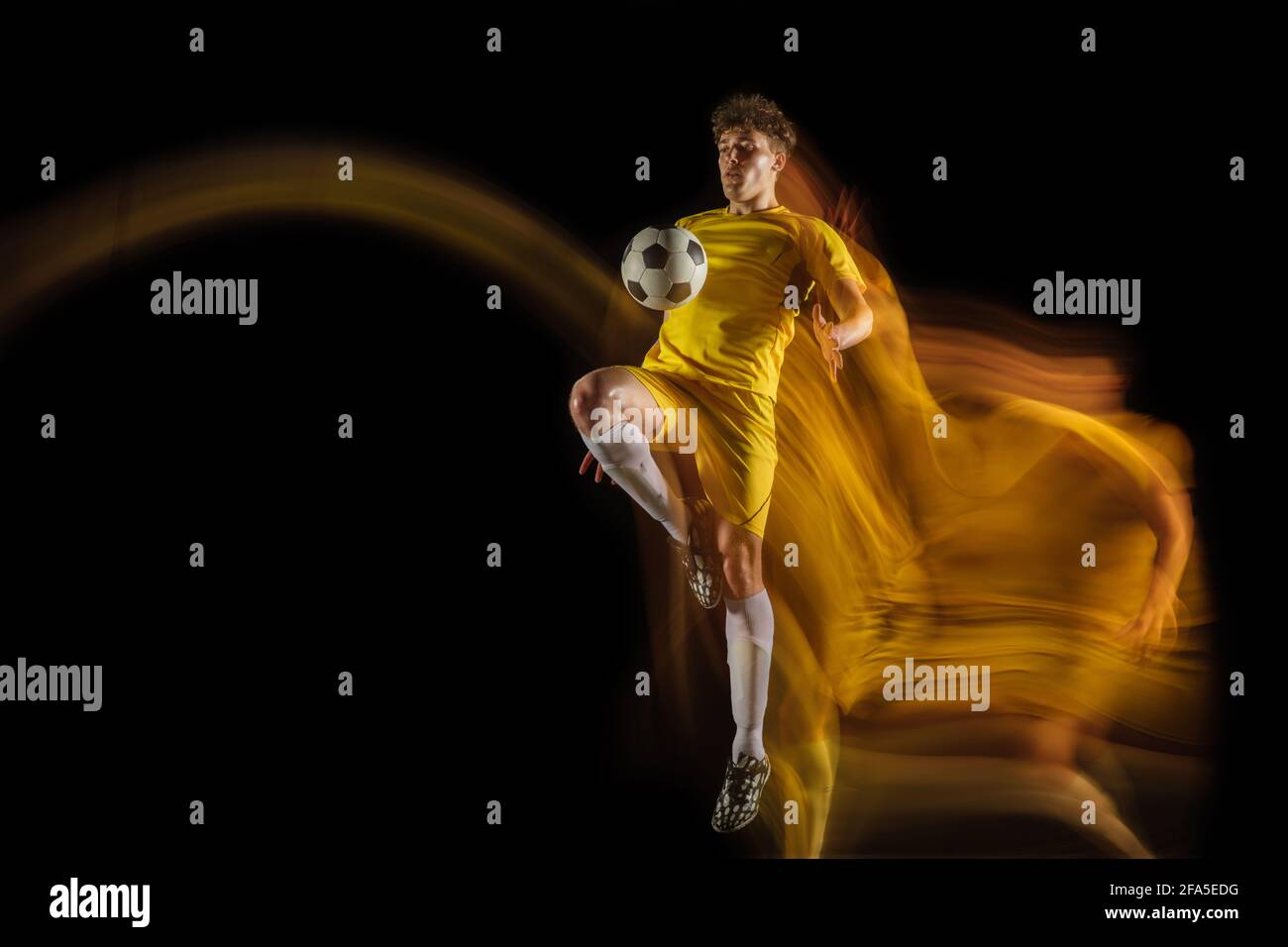 Young caucasian male football or soccer player kicking ball for the