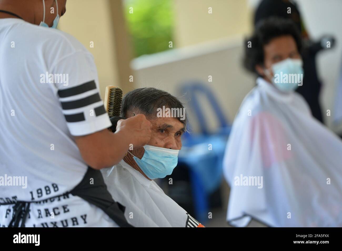 Bangkok, Thailand. 23rd Apr, 2021. A barber volunteer cuts hair for local residents in Bangkok, Thailand, April 23, 2021. Thailand's total COVID-19 cases have surpassed 50,000 as a record of 2,070 new infections were recorded on Friday, according to the Center for COVID-19 Situation Administration (CCSA). The total tally now stands at 50,183, CCSA spokesman Taweesin Visanuyothin said. Credit: Rachen Sageamsak/Xinhua/Alamy Live News Stock Photo